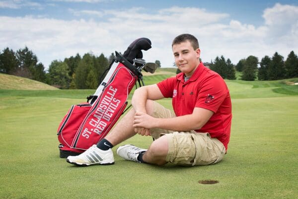 A man sitting on the ground with his golf bag.