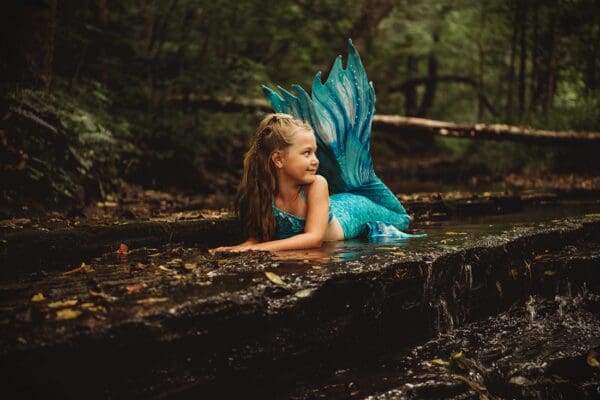 A little girl in a blue dress laying on the ground