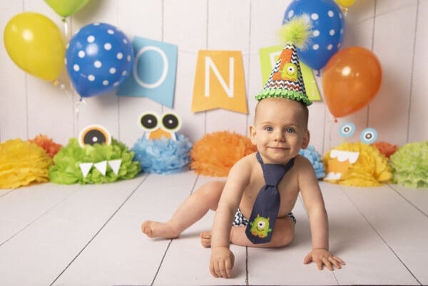 A baby boy wearing a tie and a party hat.